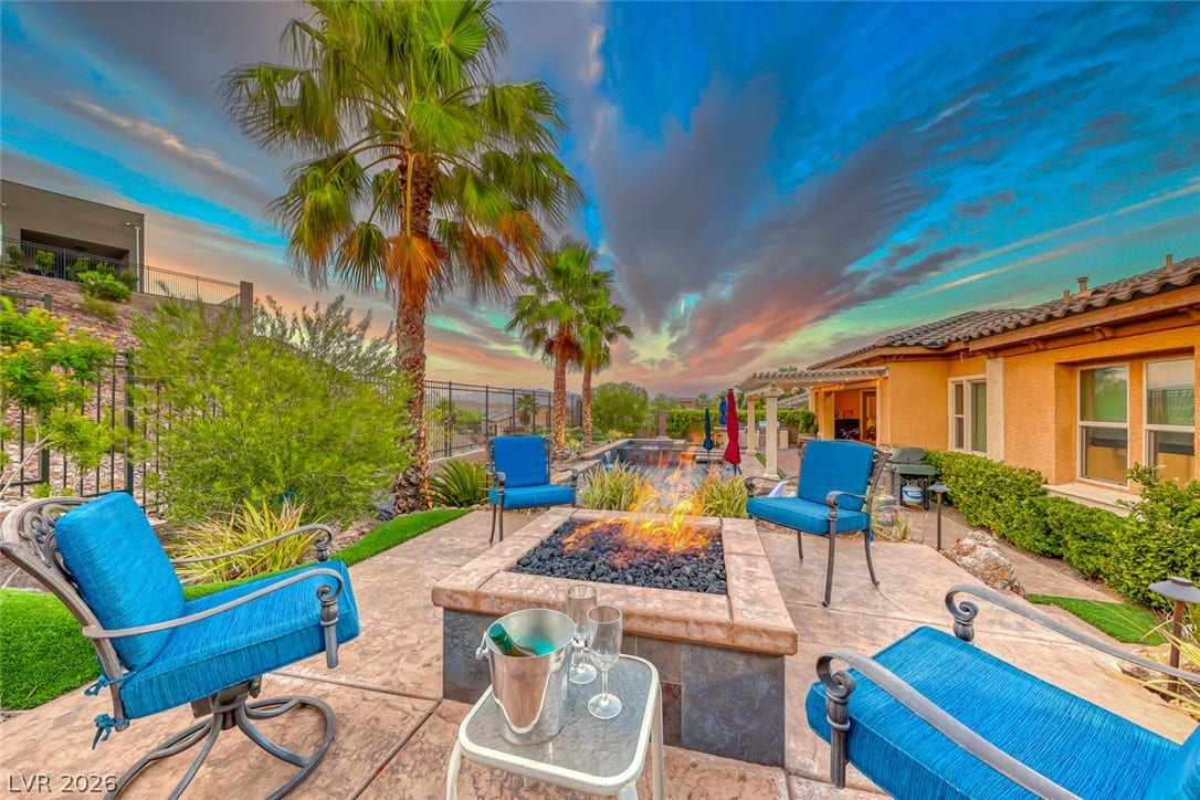 70 Portezza Drive, Henderson, NV 89011 An inviting backyard oasis features a fire pit, palm trees, and ample space for outdoor enjoyment.