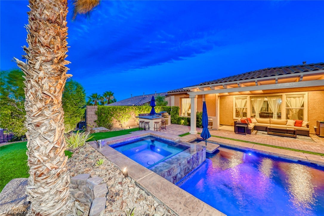 70 Portezza Drive, Henderson, NV 89011 Lush landscaping surrounds this private backyard oasis, featuring a built-in outdoor kitchen, inviting spa, and sparkling pool.