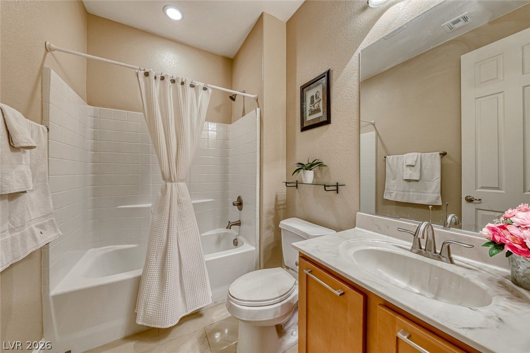70 Portezza Drive, Henderson, NV 89011 A well-lit bathroom features a tub-shower combination, a vanity with a sleek countertop, and modern fixtures.