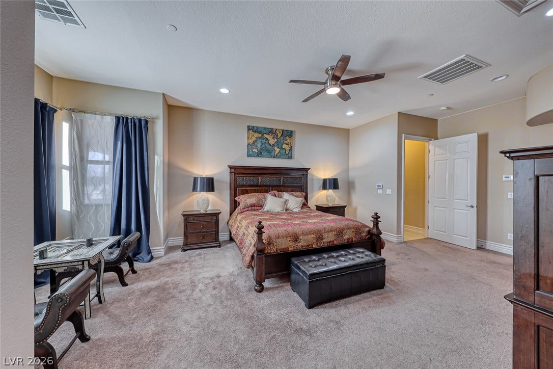 70 Portezza Drive, Henderson, NV 89011 Recessed lighting and a ceiling fan illuminate this spacious bedroom with soft, carpeted flooring.