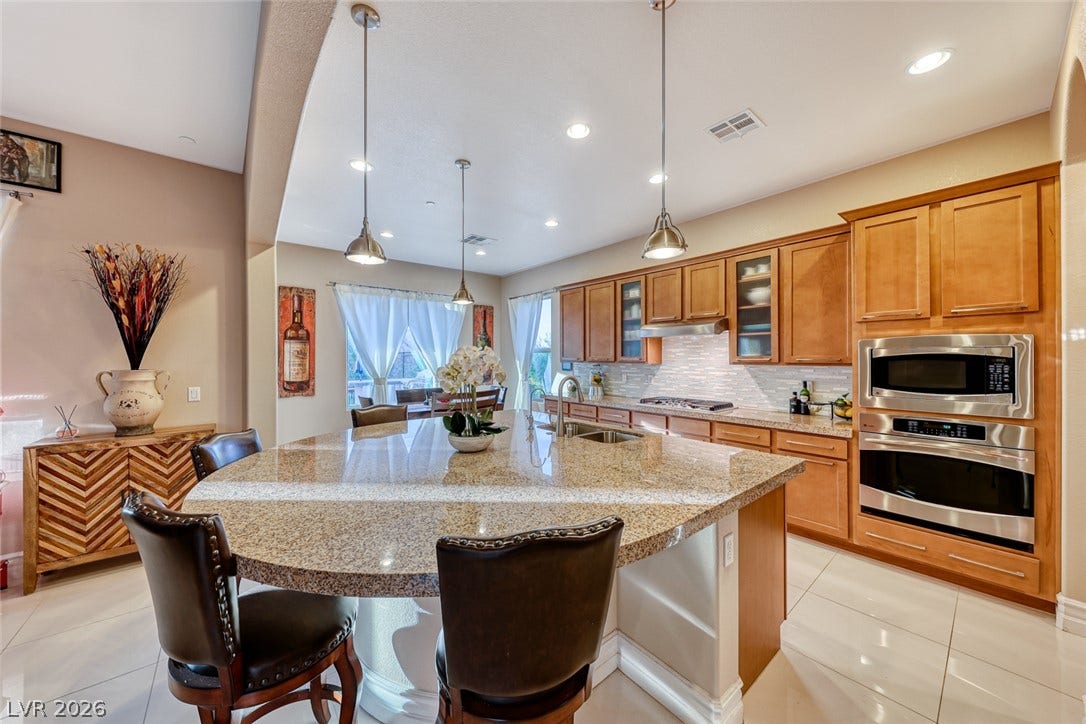 70 Portezza Drive, Henderson, NV 89011 A well-appointed kitchen features a large granite island and integrated stainless steel appliances, perfect for culinary endeavors.