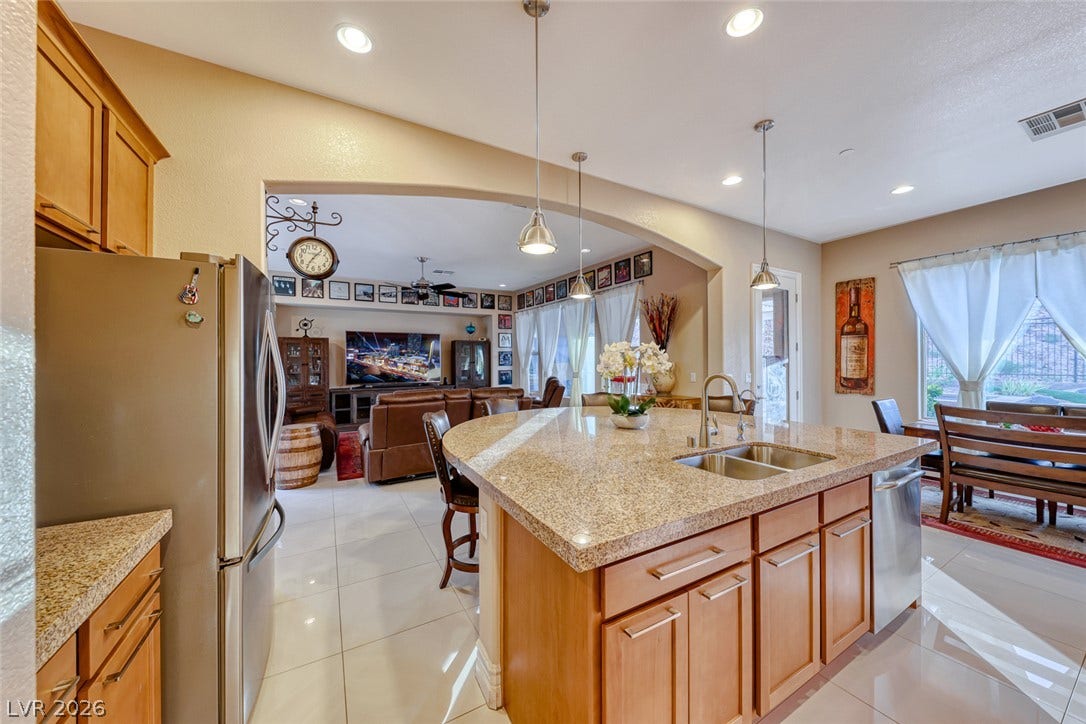 70 Portezza Drive, Henderson, NV 89011 A luminous kitchen island with granite counters and recessed lighting seamlessly flows into a welcoming living space.