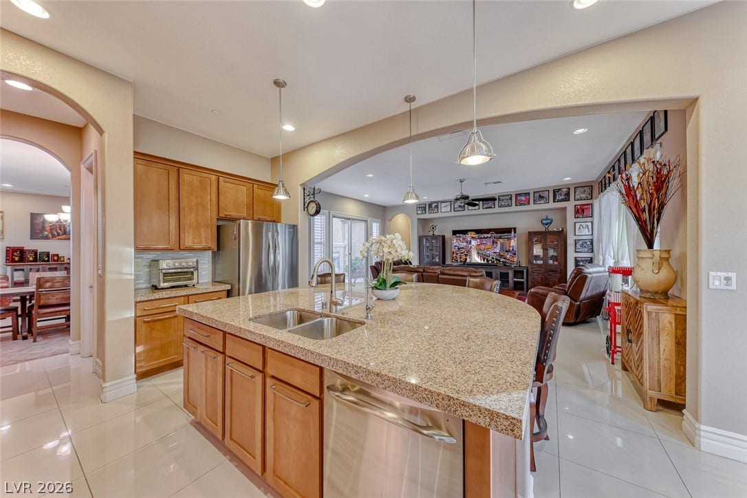 70 Portezza Drive, Henderson, NV 89011 A grand archway connects a well-appointed kitchen with an inviting open-concept living area, perfect for entertaining.