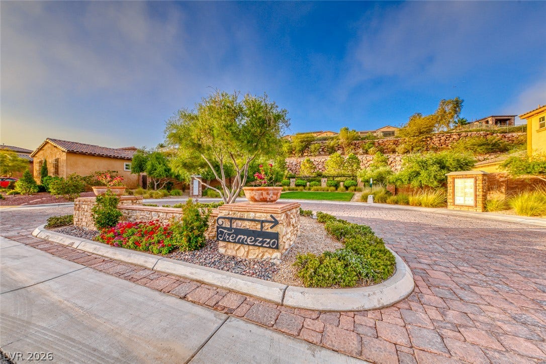 70 Portezza Drive, Henderson, NV 89011 Enter this well-maintained community through a paved, decorative stone entrance, featuring a sign, lush plantings, and vibrant florals.
