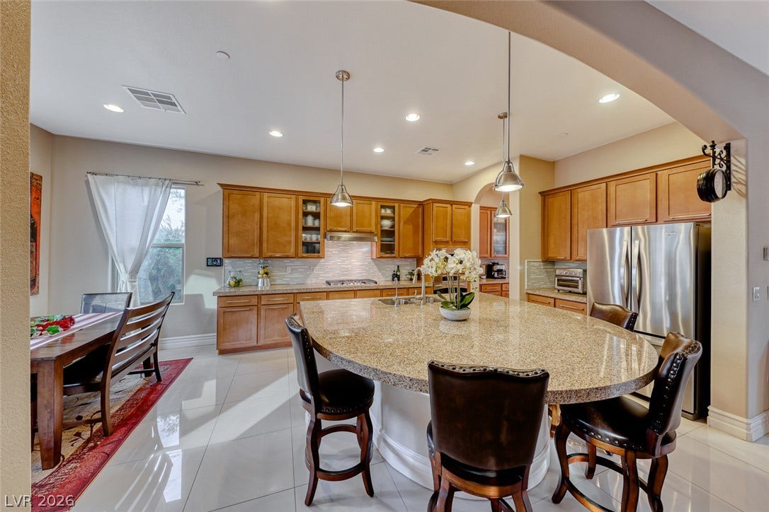 70 Portezza Drive, Henderson, NV 89011 Culinary delights await in this spacious kitchen featuring a generous island with seating and luminous recessed lighting.