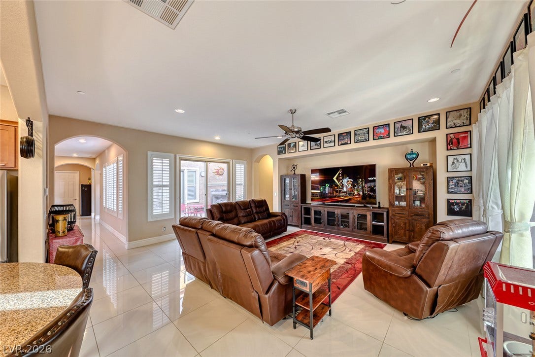 70 Portezza Drive, Henderson, NV 89011 A comfortable living area with gleaming tiled floors and a ceiling fan, connecting to an outdoor patio space.