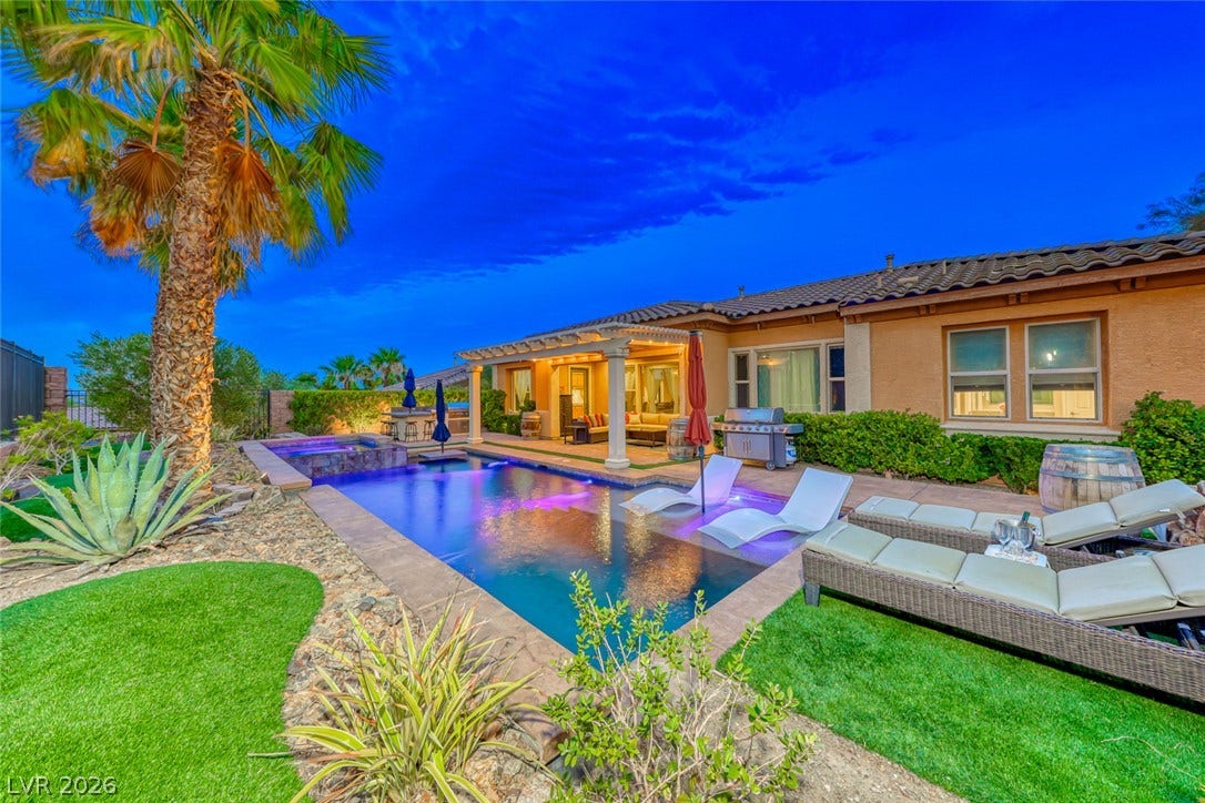 70 Portezza Drive, Henderson, NV 89011 A tranquil backyard oasis features a glistening pool, inviting lounge areas, and lush desert-adapted landscaping.
