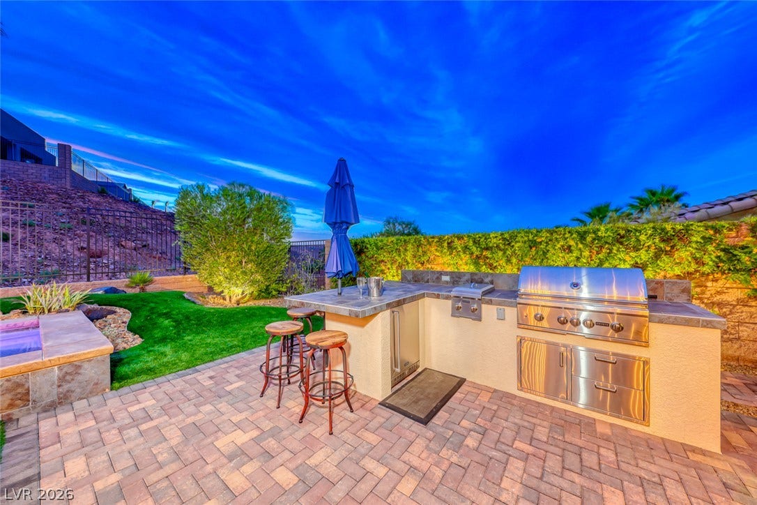 70 Portezza Drive, Henderson, NV 89011 An inviting outdoor kitchen and patio area for alfresco dining and entertaining.