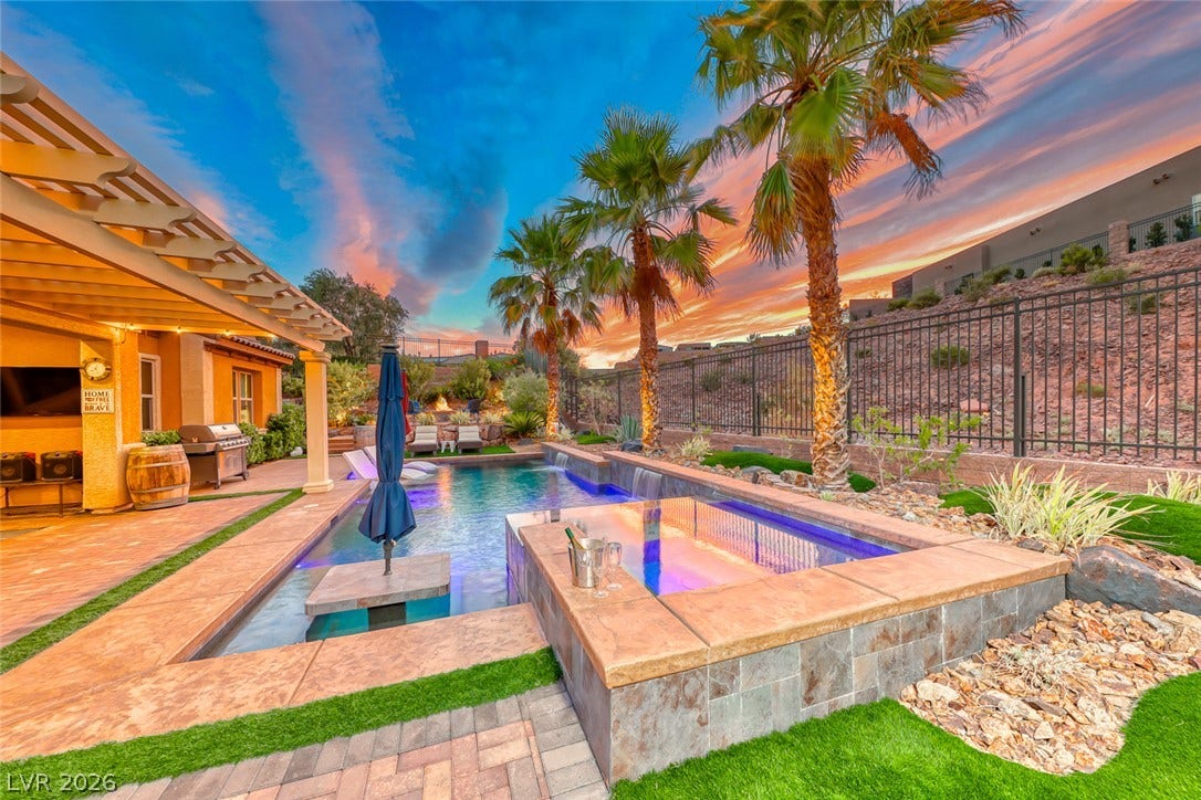 70 Portezza Drive, Henderson, NV 89011 An inviting backyard oasis offers a sparkling pool and spa, perfect for evening relaxation under a vibrant sunset.