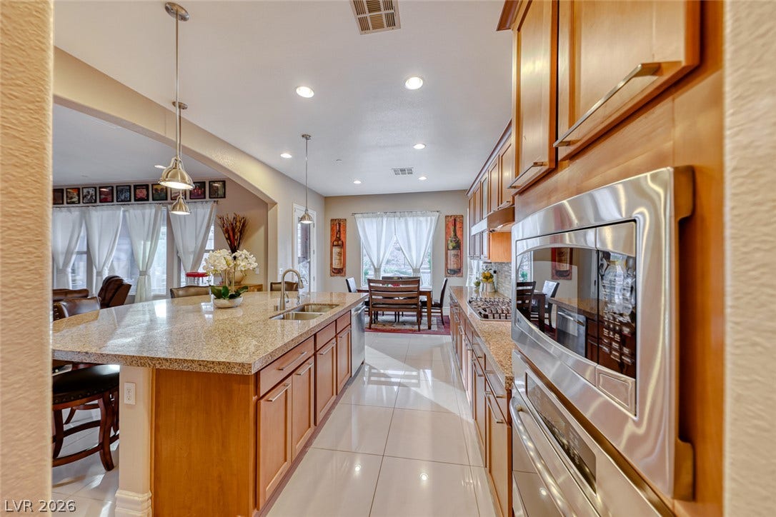 70 Portezza Drive, Henderson, NV 89011 Culinary creations come to life in this spacious kitchen, featuring a generous island and sleek appliances.