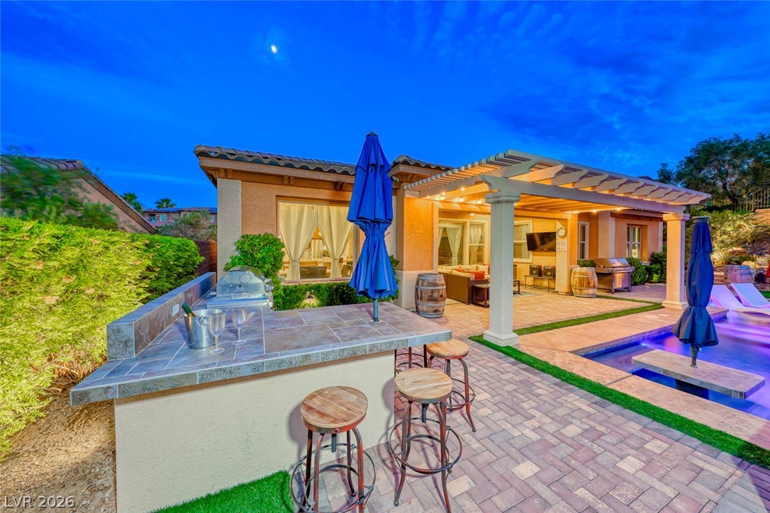 70 Portezza Drive, Henderson, NV 89011 An inviting outdoor oasis features a built-in barbecue station, a welcoming patio, and a refreshing pool under an open pergola.