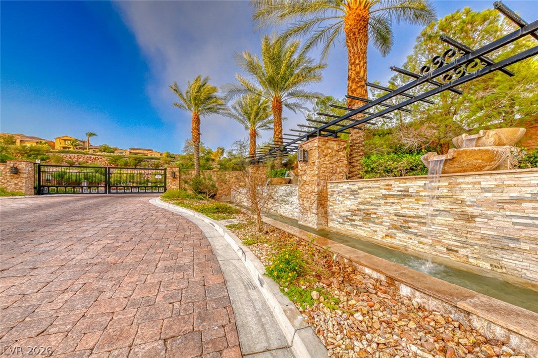 70 Portezza Drive, Henderson, NV 89011 Secure community entry with a gated entrance and a serene water feature, all under a bright sky.
