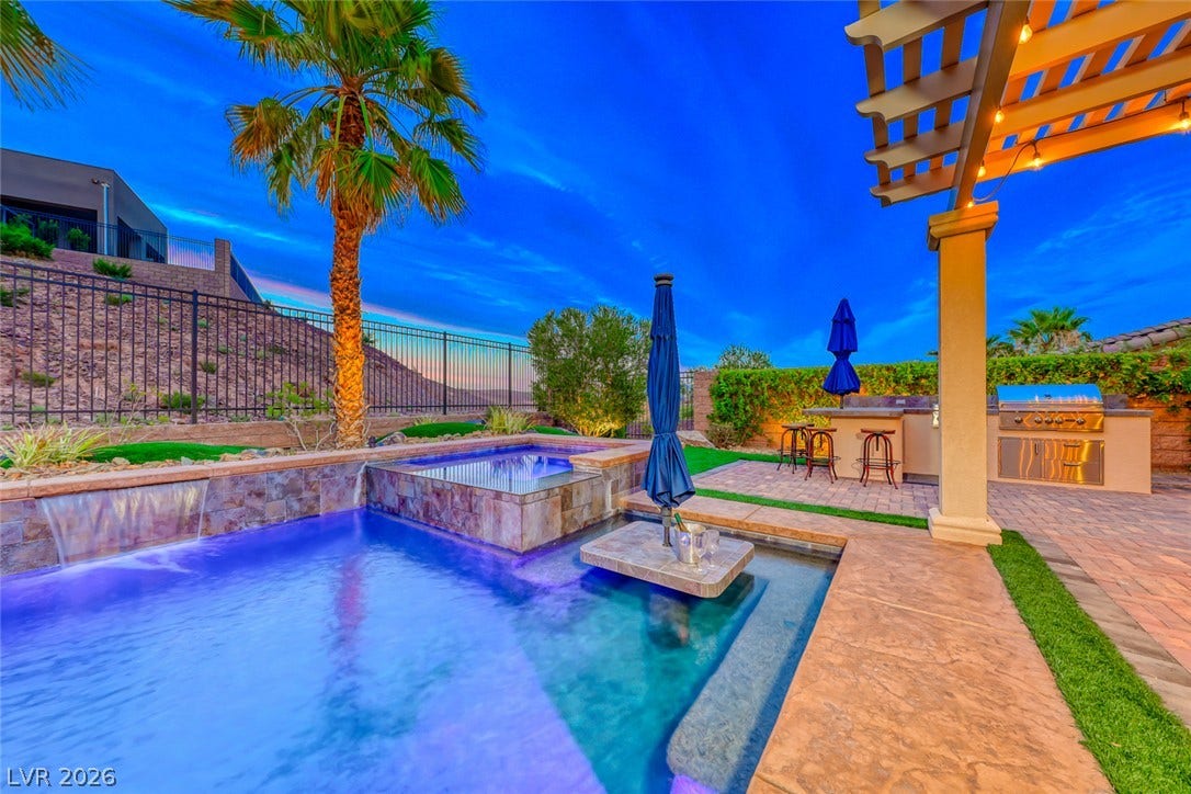 70 Portezza Drive, Henderson, NV 89011 An inviting pool area boasts a spa, waterfalls, and a full outdoor kitchen, perfect for entertaining.