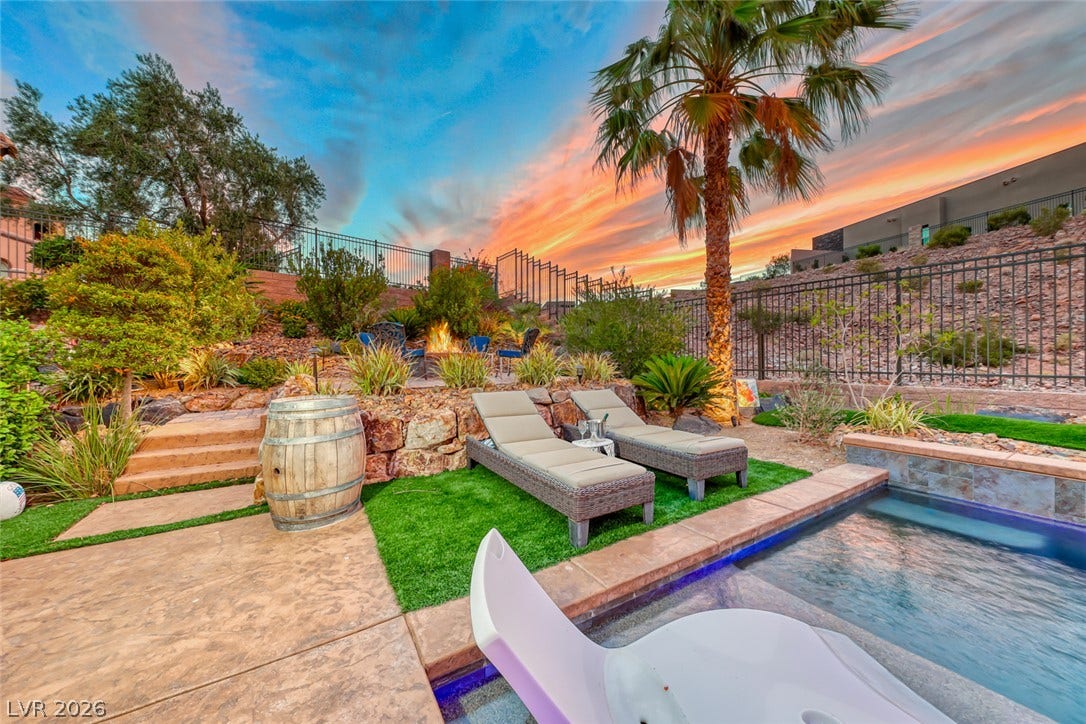 70 Portezza Drive, Henderson, NV 89011 An inviting pool area with a fire pit, chaise lounges, and mature landscaping for resort-style relaxation.
