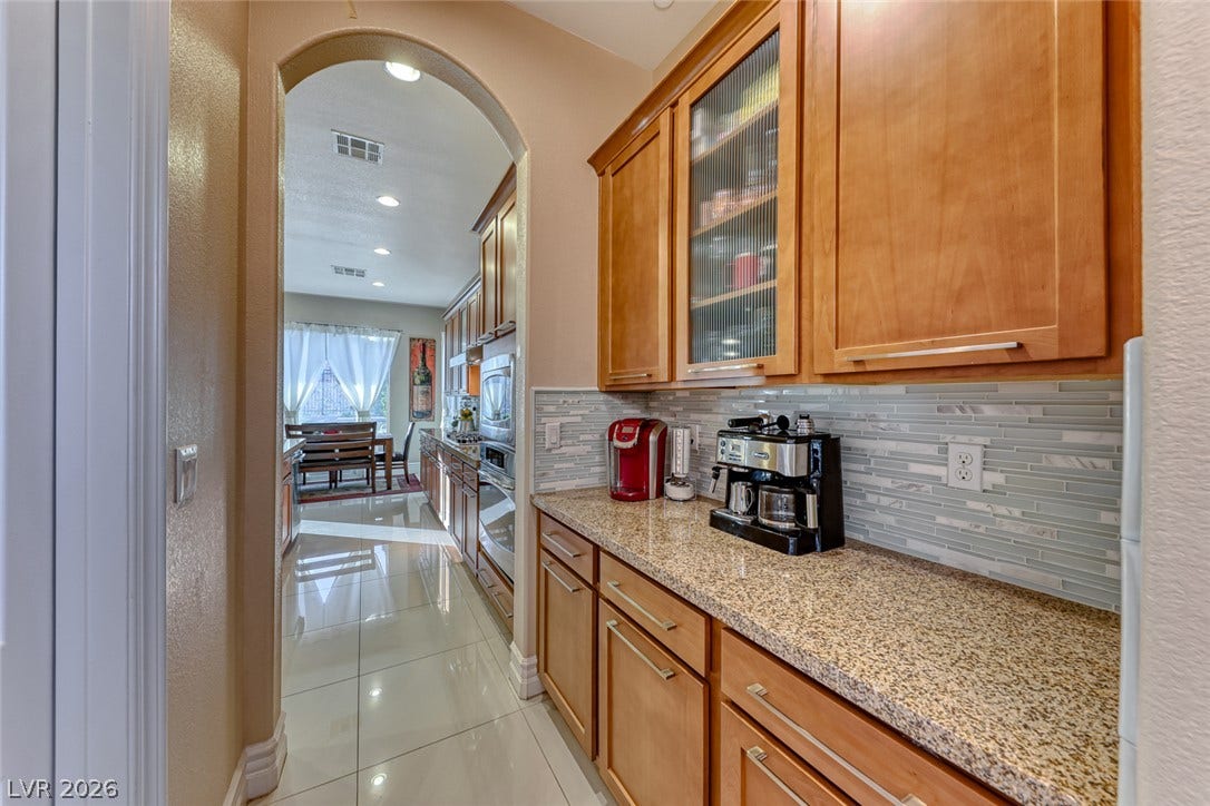 70 Portezza Drive, Henderson, NV 89011 A well-appointed kitchen showcasing elegant granite counters and a stylish tile backsplash.