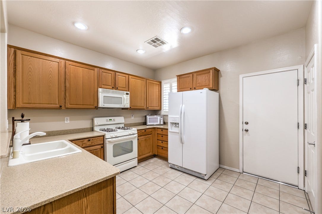 2439 Erastus Drive, Henderson, NV 89044 Kitchen with Upgraded Cabinets, Corian Counters, Recessed Lighting, Pantry, Tile Flooring,Refrigerator, Gas Stove, Dishwasher, andMicrowave