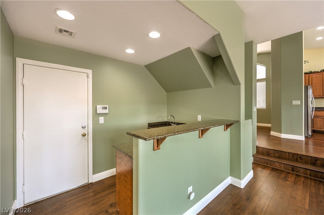 260 Quail Ranch Drive, Henderson, NV 89015 A well-appointed wet bar with granite countertops and rich wood flooring offers a perfect spot for entertaining.