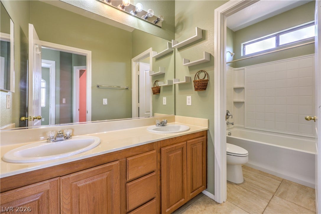 260 Quail Ranch Drive, Henderson, NV 89015 A twin-sink vanity with light wood cabinetry and a combined tub and shower provide a functional bathroom space.