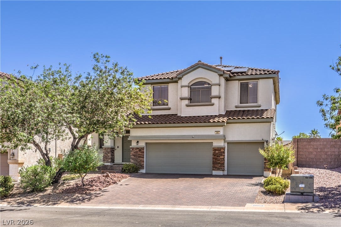 260 Quail Ranch Drive, Henderson, NV 89015 A cream-colored stucco home features a three-car garage, solar panels, and a stone-tiled roof