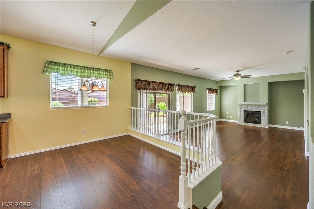 260 Quail Ranch Drive, Henderson, NV 89015 Rich hardwood flooring flows through this airy living area, highlighting a cozy fireplace and sunlit dining space.