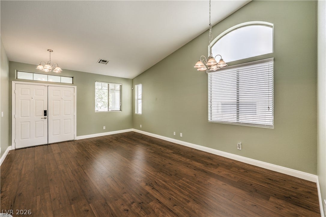260 Quail Ranch Drive, Henderson, NV 89015 Natural light cascades through a prominent arched window, illuminating the rich wood flooring in this inviting living space.