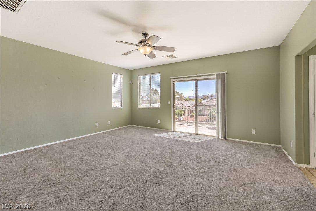 260 Quail Ranch Drive, Henderson, NV 89015 The spacious primary bedroom features plush carpeting and a glass sliding door leading to an outdoor balcony.