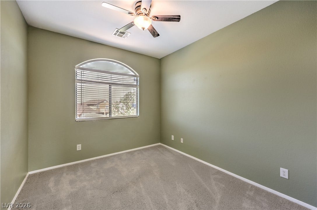260 Quail Ranch Drive, Henderson, NV 89015 A comfortable bedroom features plush carpeting and a gracefully arched window, perfect for creating a personalized sanctuary.