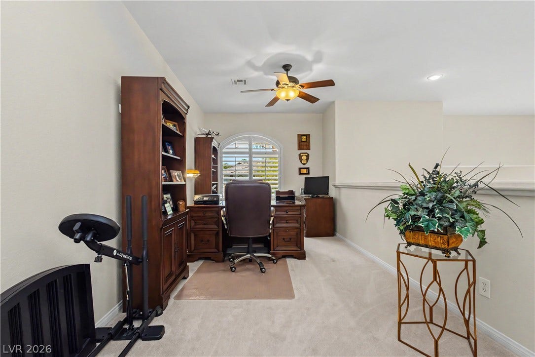 118 Serramonte Court, Henderson, NV 89074 An inviting study with built-in shelving, an arched window, and a cooling ceiling fan for comfort.
