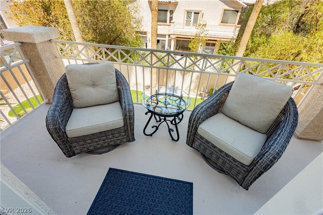 118 Serramonte Court, Henderson, NV 89074 A well-lit balcony features a white railing overlooking a tranquil neighborhood.