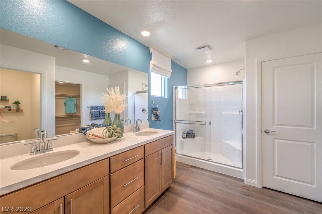 Bathroom with a shower stall, visible vents, wood finished floors, and a sink.Photos are of a model home and are for representational purposes only.