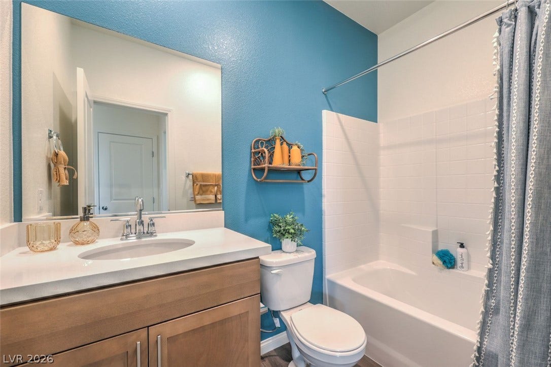 Bathroom with toilet, vanity, and shower / bath combo with shower curtain.Photos are of a model home and are for representational purposes only.