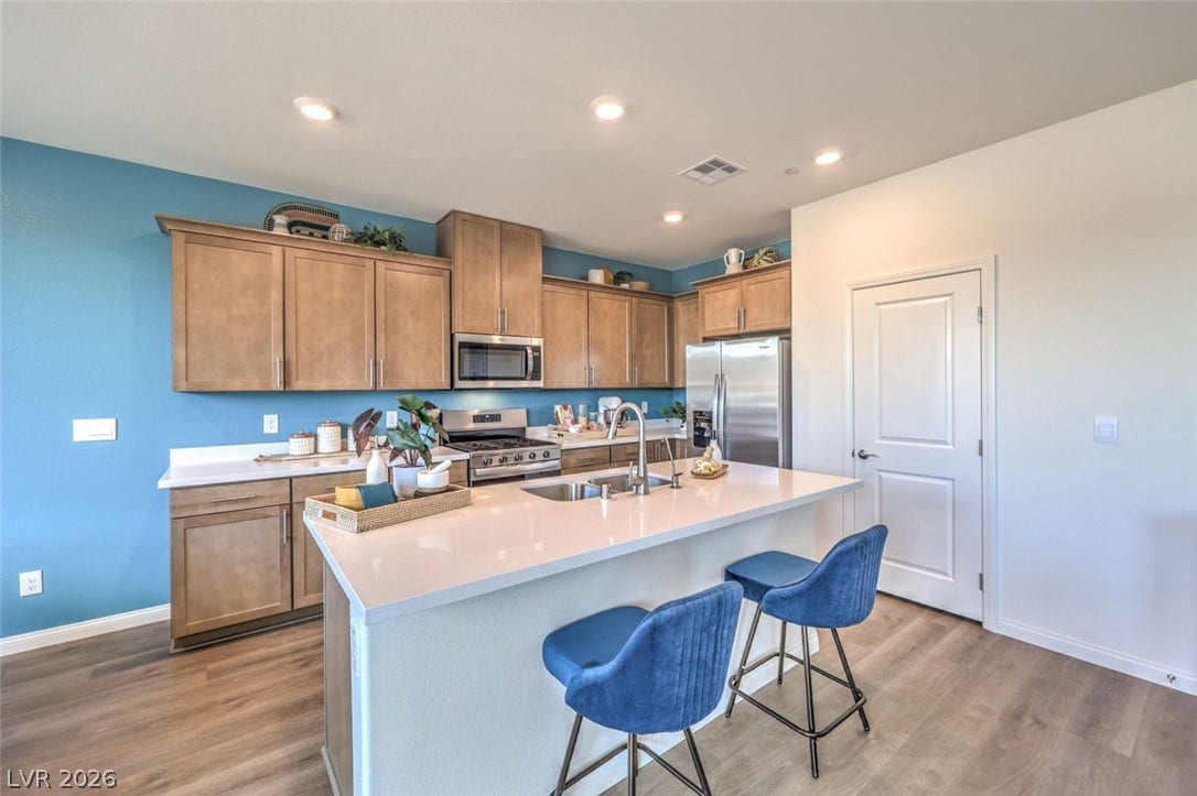 Kitchen featuring a sink, a breakfast bar, light wood-style flooring, stainless steel appliances, and visible vents.Photos are of a model home and are for representational purposes only.