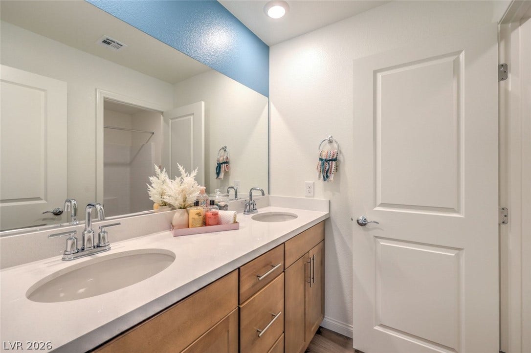 Bathroom featuring double vanity, visible vents, and a sink.Photos are of a model home and are for representational purposes only.