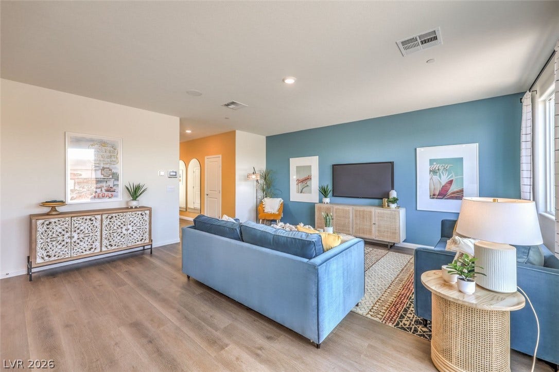 Living room featuring arched walkways, baseboards, visible vents, and wood finished floors.Photos are of a model home and are for representational purposes only.