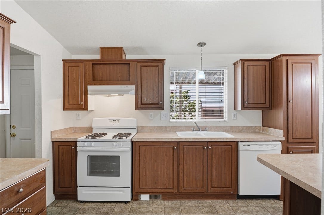 4589 Royal Ridge Boulevard, Las Vegas, NV 89103 A well-equipped kitchen features a white gas range and a double basin sink beneath a sun-filled window.