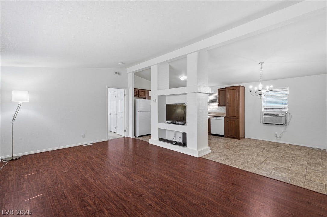 4589 Royal Ridge Boulevard, Las Vegas, NV 89103 Rich wood flooring defines this inviting open-concept living space with a distinct dining area and kitchen beyond.