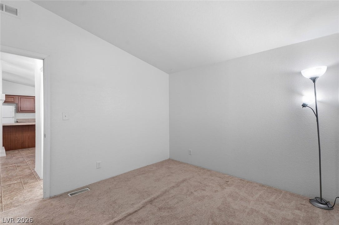 4589 Royal Ridge Boulevard, Las Vegas, NV 89103 An inviting room boasts soft carpeting and a glimpse into an adjacent kitchen space.