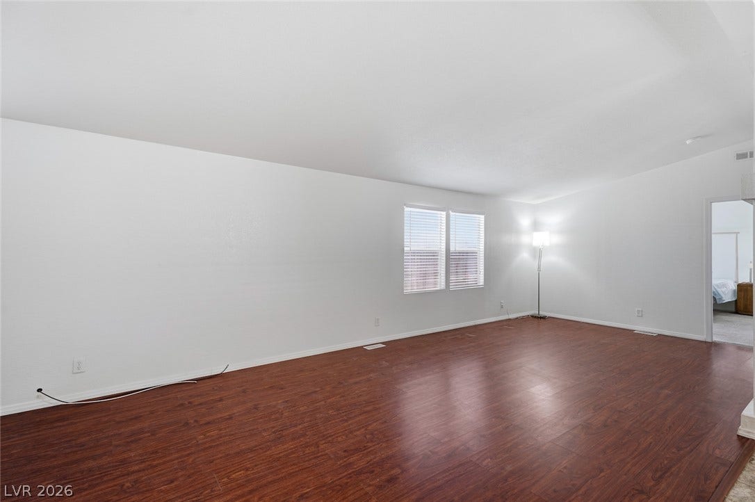 4589 Royal Ridge Boulevard, Las Vegas, NV 89103 Rich wood-look flooring extends through this naturally illuminated living space, offering an inviting atmosphere.