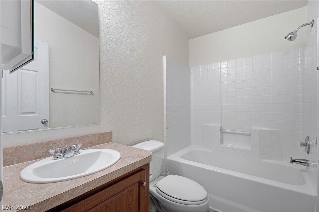 4589 Royal Ridge Boulevard, Las Vegas, NV 89103 A well-appointed bath features a sleek vanity and a pristine tub with tiled surround.