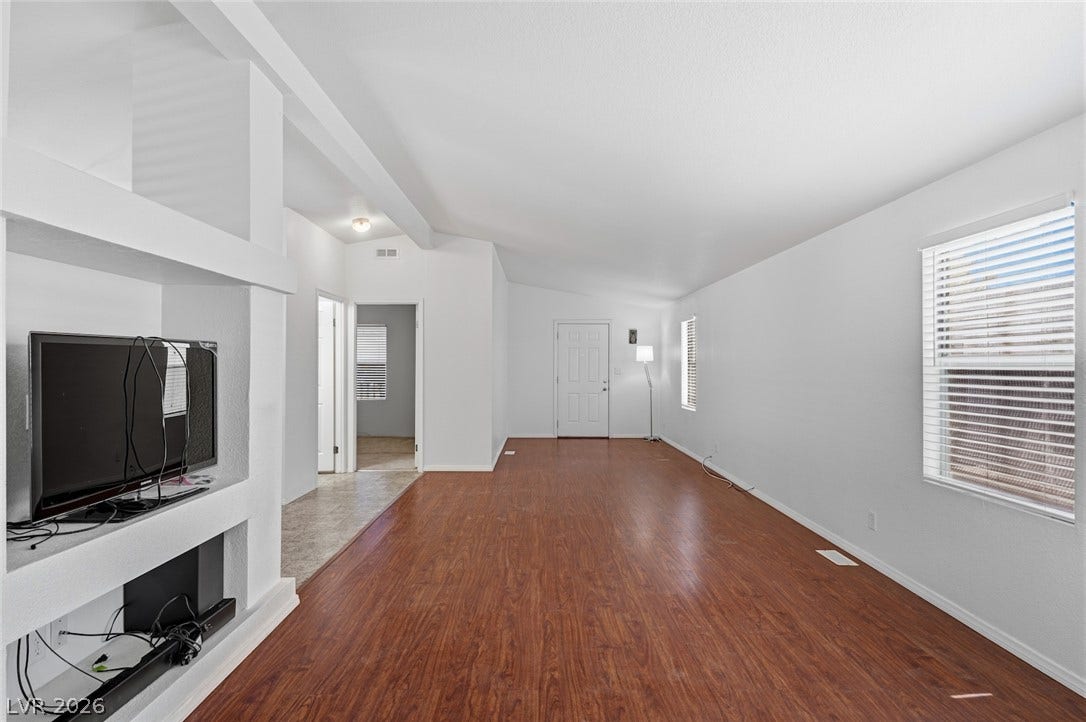 4589 Royal Ridge Boulevard, Las Vegas, NV 89103 A spacious living area features rich hardwood flooring and sun-filled windows, creating an inviting atmosphere.