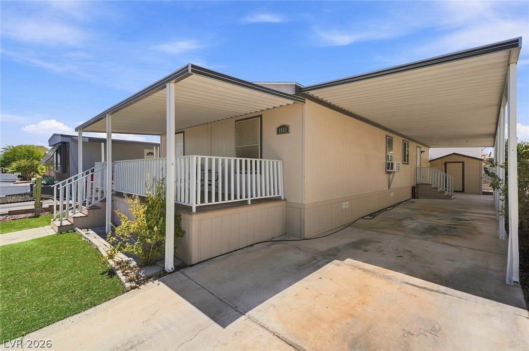 4589 Royal Ridge Boulevard, Las Vegas, NV 89103 A well-maintained manufactured home features a practical carport, covered porch, and accessible steps, ready for comfortable living.