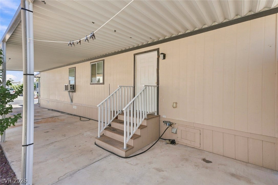4589 Royal Ridge Boulevard, Las Vegas, NV 89103 A side entrance with steps leads to a manufactured home, sheltered by an extended carport roof.