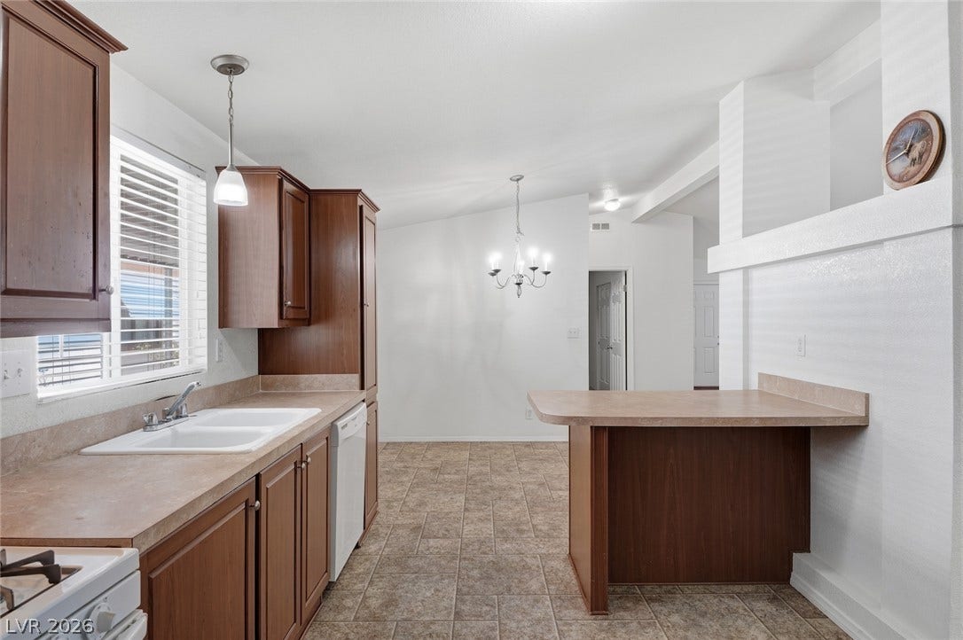 4589 Royal Ridge Boulevard, Las Vegas, NV 89103 Well-lit kitchen with rich cabinetry and an inviting dining area beyond the breakfast bar.