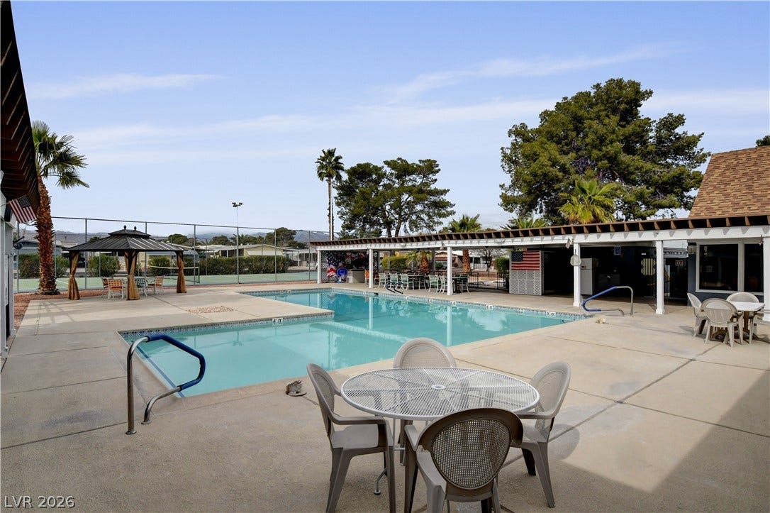 4589 Royal Ridge Boulevard, Las Vegas, NV 89103 An inviting outdoor community pool area, complete with shaded lounge spots and nearby tennis courts, offers leisure and recreation.