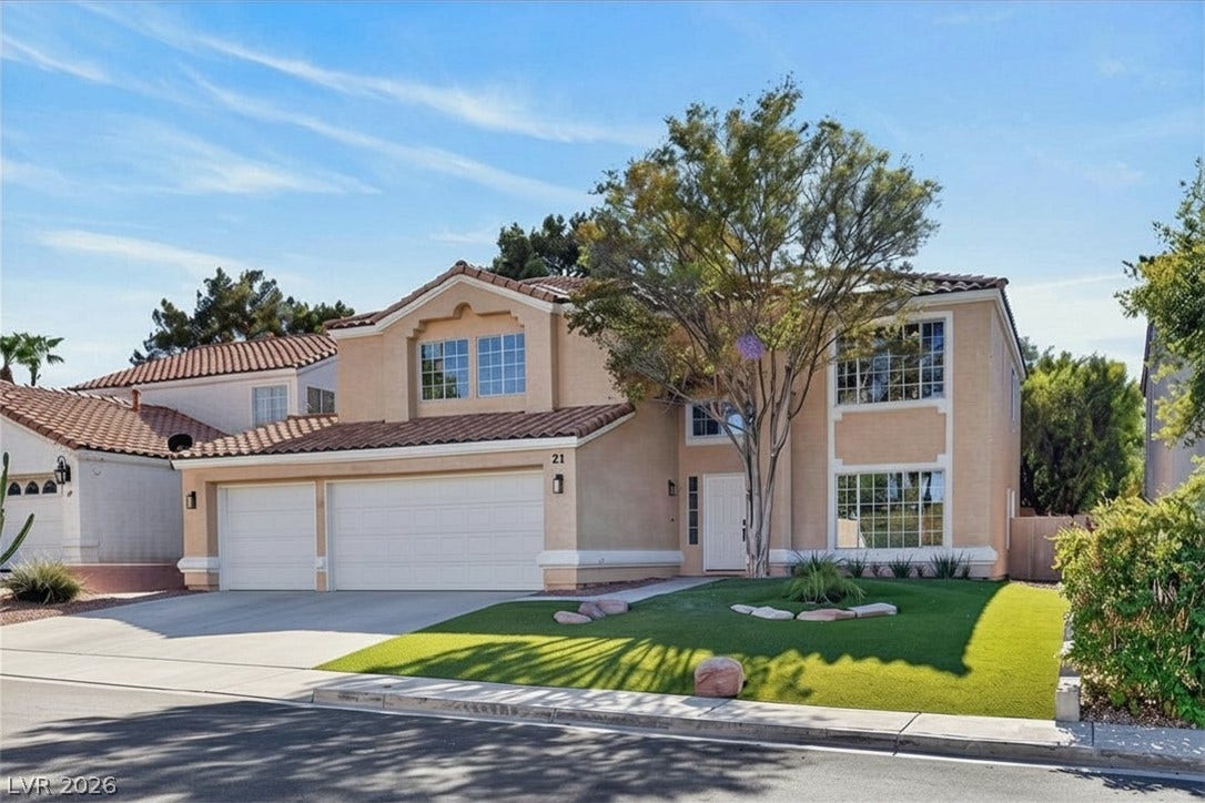 21 Antero Drive, Henderson, NV 89074 Two-story desert contemporary home with an inviting green lawn and concrete driveway.