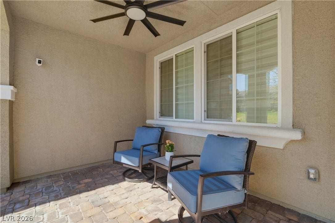 An inviting covered patio features a ceiling fan, offering a tranquil outdoor retreat.