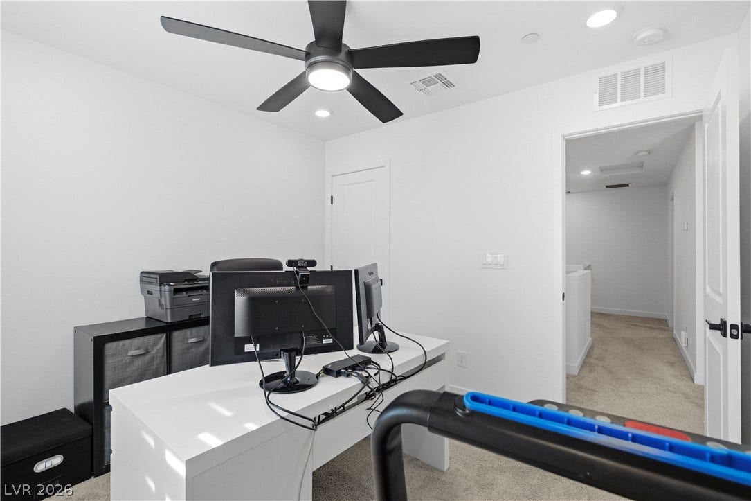 Well-lit office area offers recessed lighting and a sleek ceiling fan for comfort and productivity.