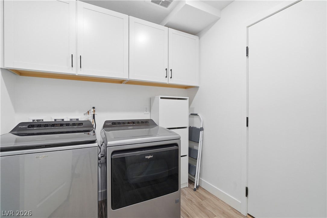 Streamlined laundry room features overhead cabinetry for organized storage, ensuring efficiency.