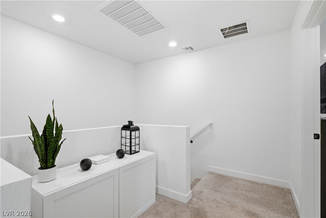 A well-lit landing area with recessed lighting and carpeted stairs invites residents to ascend or descend.