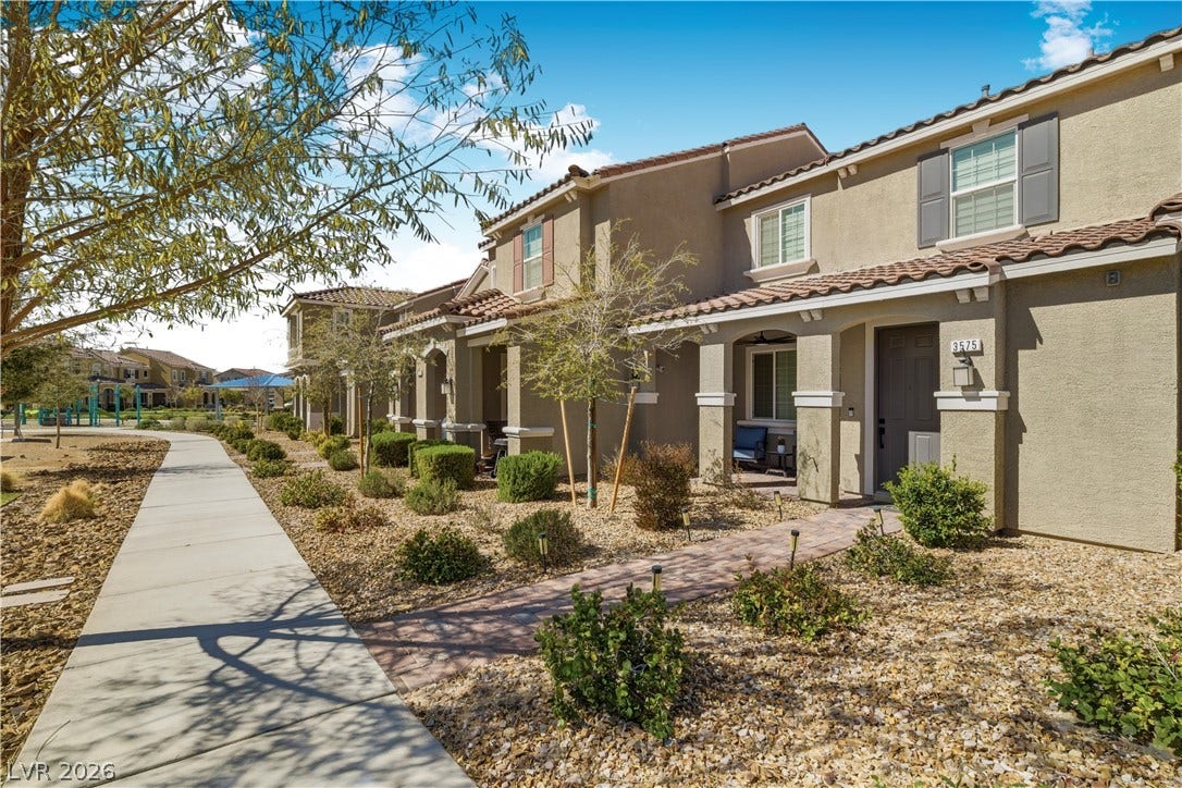 A welcoming walkway leads to these inviting townhomes with covered front porches, complemented by desert-friendly landscaping.